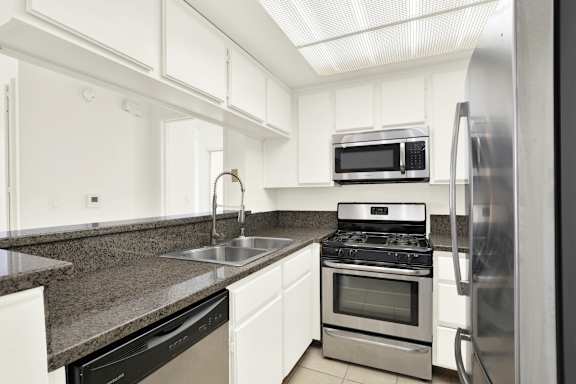 A kitchen with a black countertop and stainless steel appliances at Peach Tree Court, Los Angeles, 90024