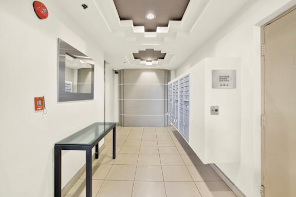 A long hallway with a glass table and a mirror on the wall.