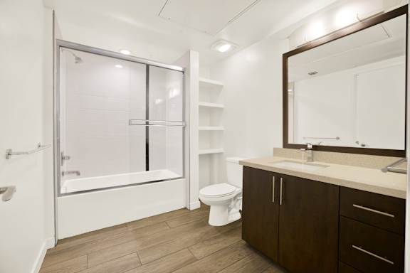 A bathroom with a toilet, sink, and a bathtub with a glass door.