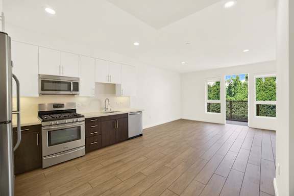 A kitchen with wooden floors and stainless steel appliances at The Urbanpolitan, Los Angeles, 90036