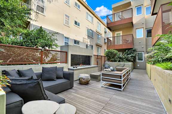 A patio with a black couch and a wooden table.