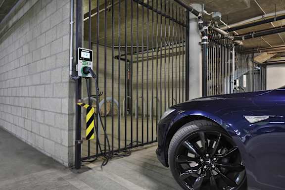 A car is parked in a garage next to a gate with a digital display.