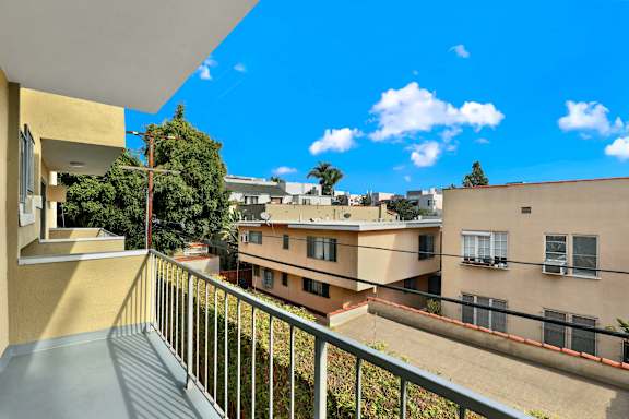 A balcony overlooks a courtyard with buildings and trees.