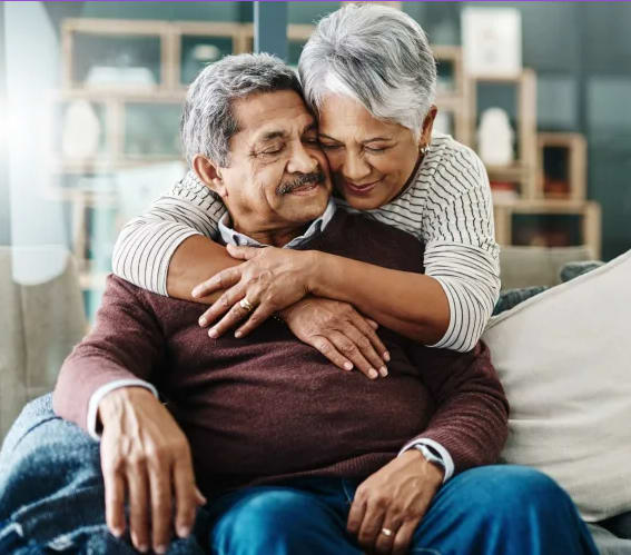 an older couple sitting on a couch with their arms around each other