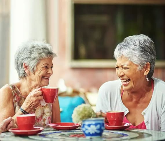 a couple of women sitting at a table with cups of coffee