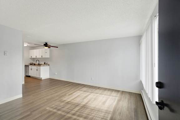 A room with a ceiling fan and a cabinet with a sink.