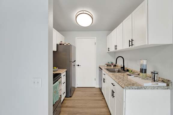 A kitchen with white cabinets and a granite countertop.