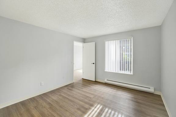 A room with a wooden floor and a window with blinds.