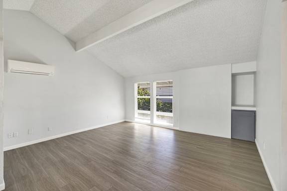 A spacious room with wooden flooring and a large window.