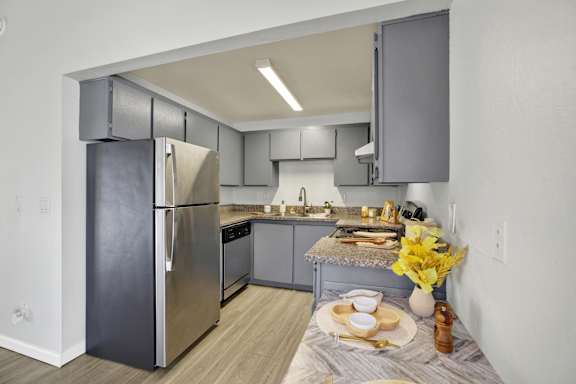 A modern kitchen with a stainless steel refrigerator and a table set for two.