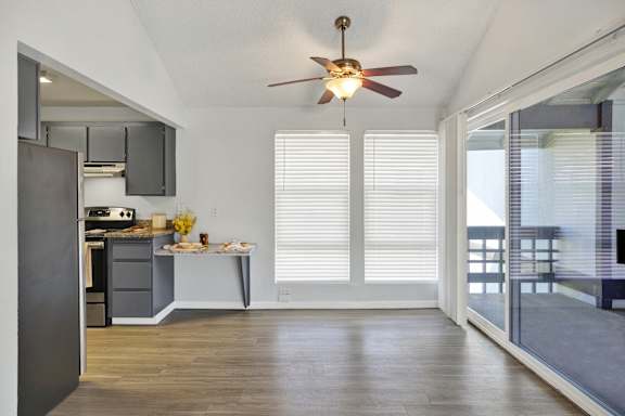 A kitchen with a ceiling fan and a dining table with chairs.