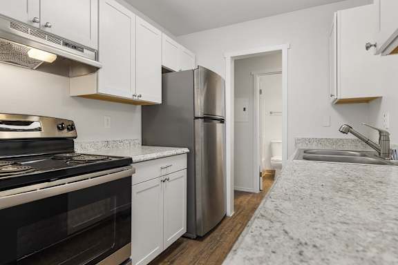 Floor Plan  A kitchen with white cabinets and a stainless steel refrigerator.