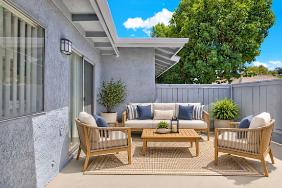 A patio with a sofa, chairs, and a table.