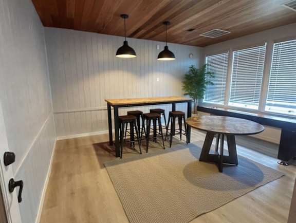 A room with a wooden ceiling and a table with four stools.