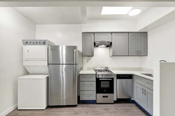 A modern kitchen with stainless steel appliances and white cabinets.at Federal Apartments, California, 90025