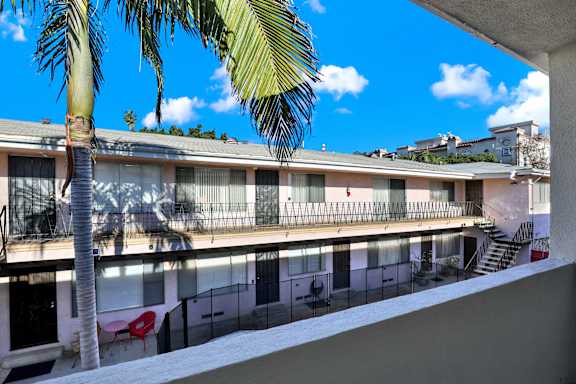 A building with a balcony and a palm tree in front.at Federal Apartments, Los Angeles