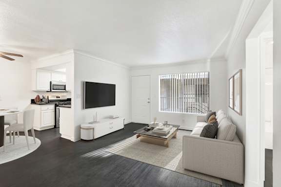 A modern living room with a grey couch and a television. at Elmwood Gardens, Burbank, 91502