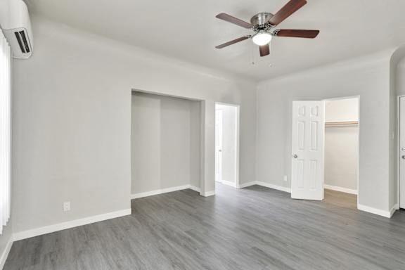 A room with a ceiling fan and light fixture, and a door on the right.at Barton Apartments, Los Angeles California