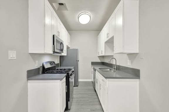 A kitchen with white cabinets and a black stove top.at Barton Apartments, Los Angeles