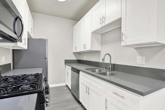 A kitchen with white cabinets and a black stove top.at Barton Apartments, Los Angeles, CA 90038