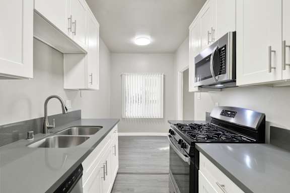 A kitchen with white cabinets and black appliances.at Barton Apartments, Los Angeles, 90038