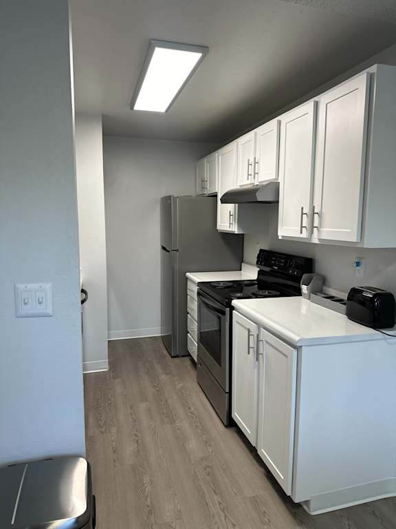 A kitchen with white cabinets and a black stove top oven.