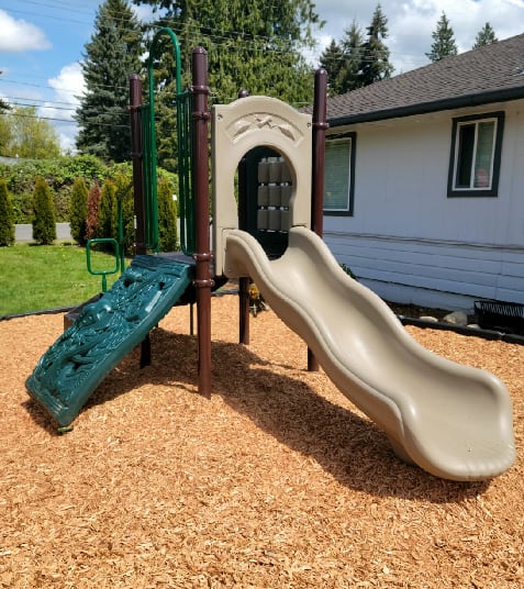 A playground with a green slide and a brown slide.