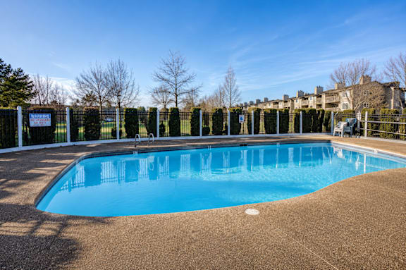 A large blue swimming pool surrounded by a fence.