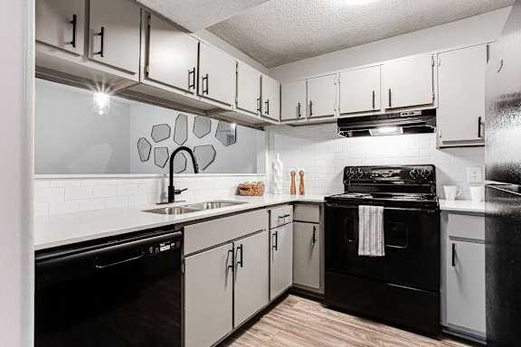 A modern kitchen with black appliances and white cabinets.at Laurel, Georgia