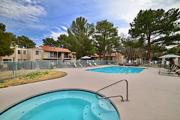 A swimming pool surrounded by trees and a fence.