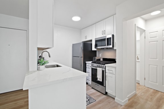 a kitchen with white cabinetry and stainless steel appliances at Harvard Manor, Irvine, CA