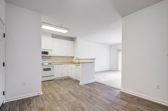 A kitchen with white cabinets and a wooden floor.