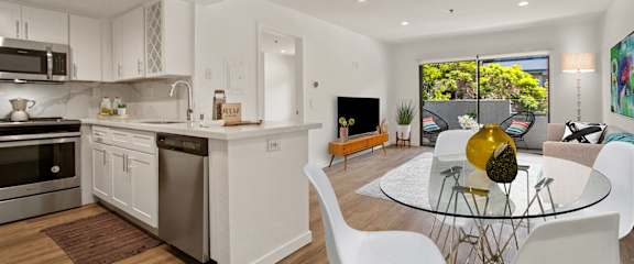 A modern kitchen with white cabinets and a glass table.