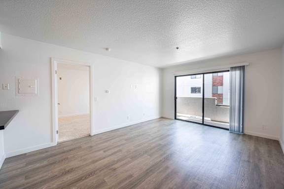 an empty living room with hardwood floors and a balcony
