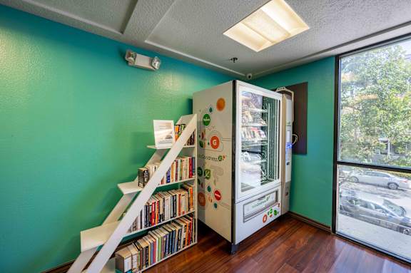 a room with a bookshelf and a refrigerator