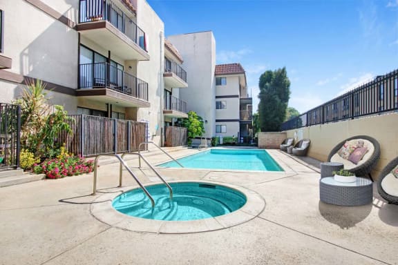a swimming pool with a hot tub in front of an apartment building