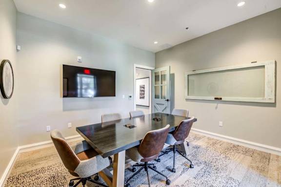 a conference room with a table and chairs and a tv on the wall at The Vineyards Apartments, California, 91326