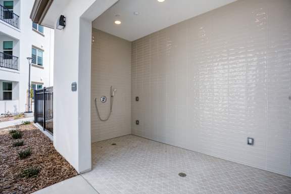A white tiled bathroom with a shower and a toilet at Pradera Apartments, San Ramon, CA,  94582