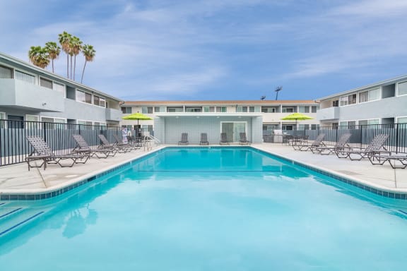 a swimming pool with chaise lounge chairs and umbrellas  at Park Apartments, Norwalk, CA, 90650