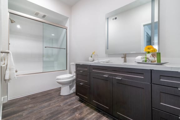a bathroom with white walls and a wooden floor  at Montecito Apartments at Carlsbad, Carlsbad, 92010