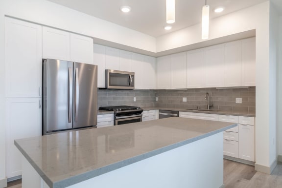 a kitchen with white cabinets and a large island  at Montecito Apartments at Carlsbad, Carlsbad