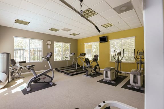 a fitness center with treadmills and other exercise equipment  at Tesoro Senior Apartments, Porter Ranch