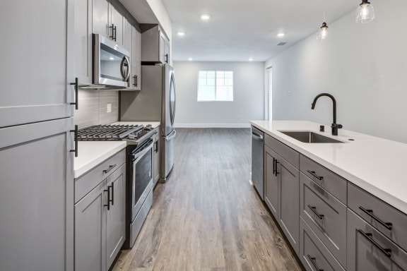 a kitchen with gray cabinets and white countertops at The Vineyards Apartments, California, 91326