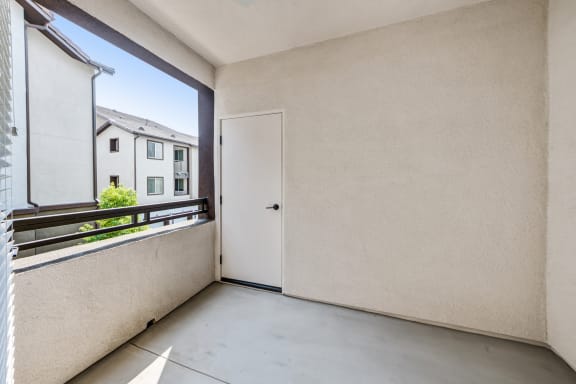 a bedroom with a large window and a door that leads to a balcony at The Vineyards Apartments, California, 91326