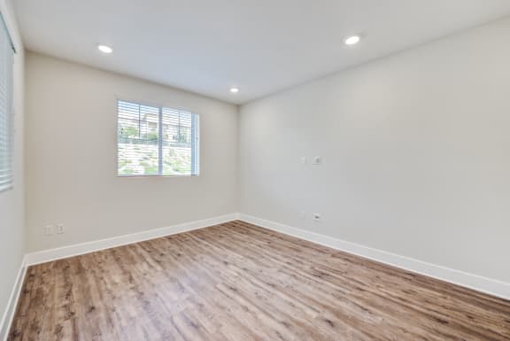 a bedroom with hardwood floors and a window at The Vineyards Apartments, Porter Ranch, CA, 91326