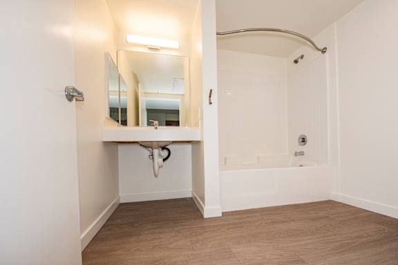 A white bathroom with a tub and a mirror.