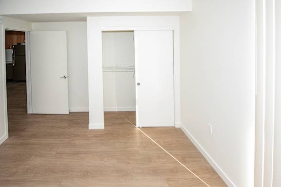 A room with a white door and a white wall and closet.