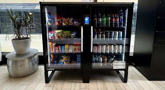 A black vending machine with a variety of snacks and drinks inside.
