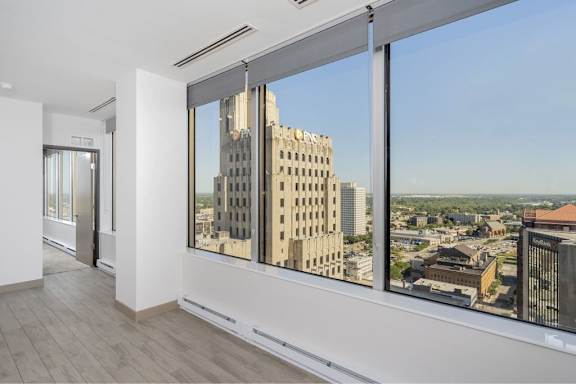 A room with a view of a cityscape through large windows.