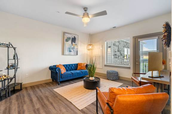 a living room with a blue couch and a ceiling fan at 41 North Senior Living Apartments, Fort Wayne, IN, 46835